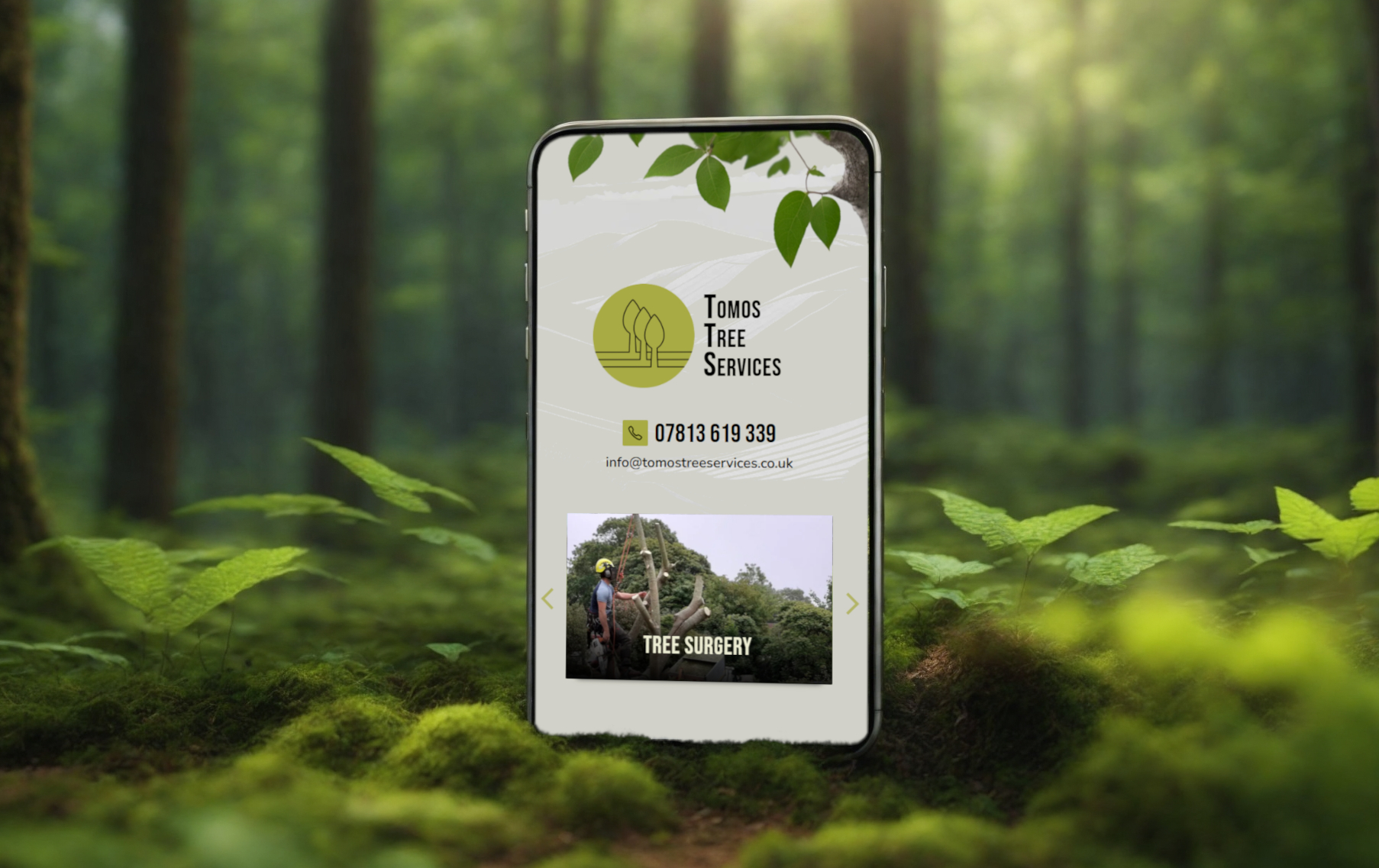 Smartphone displaying Tomos Tree Services website, nestled in serene Welsh forest landscape.