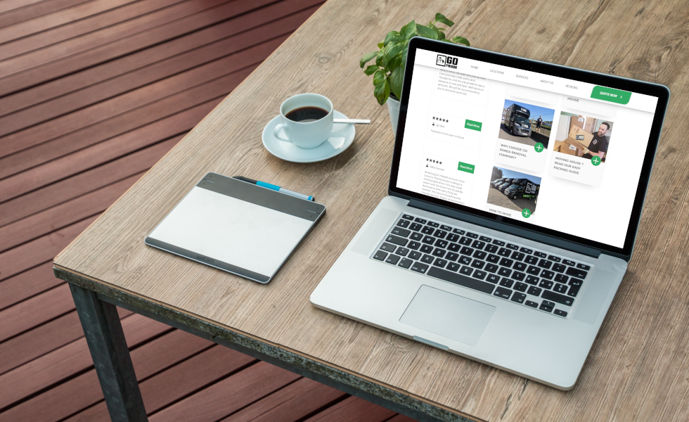 Laptop displaying modern web portfolio on a wooden desk with coffee and notepad, showcasing digital craftsmanship in Wales.